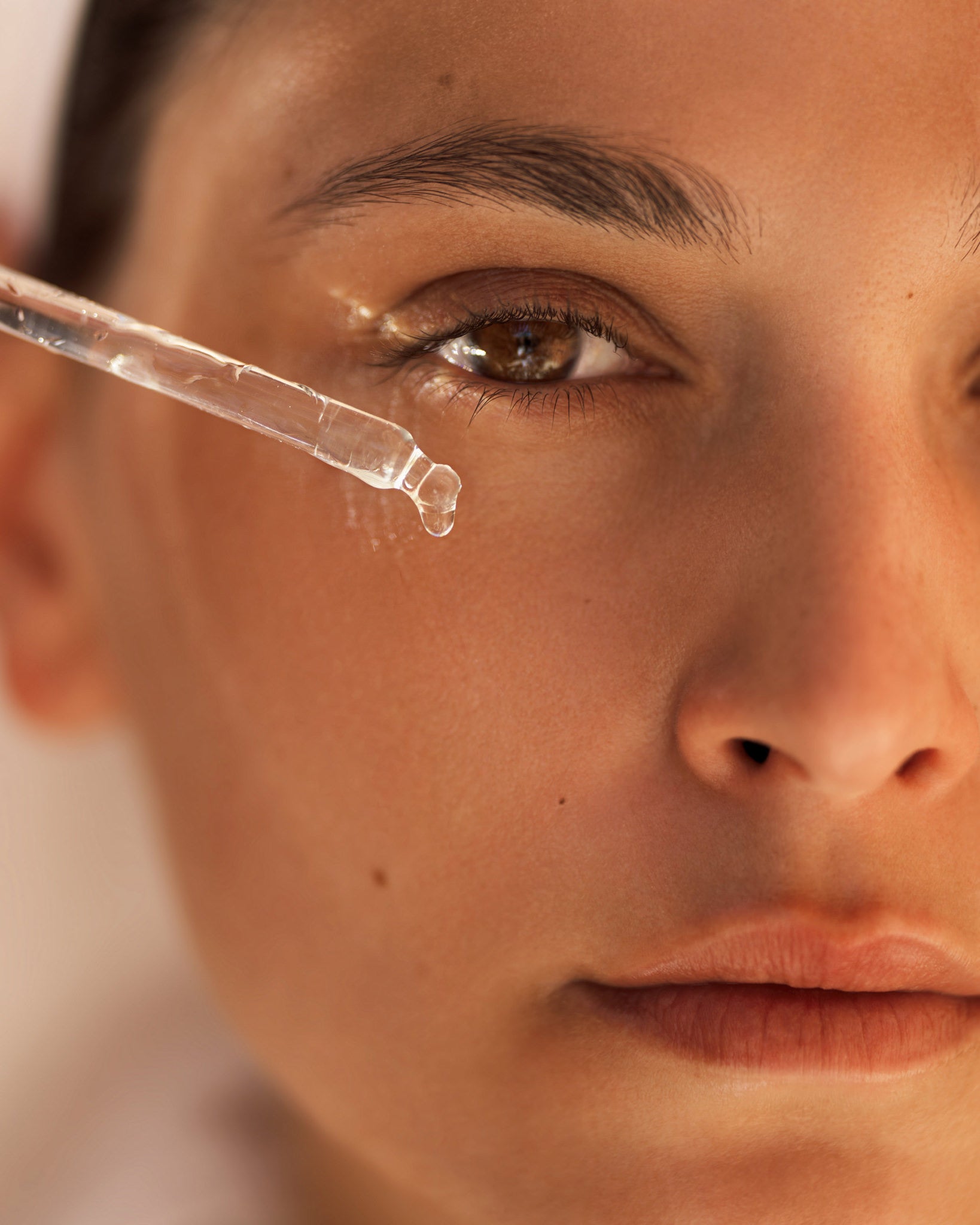 A close-up of skin and a glass dropper