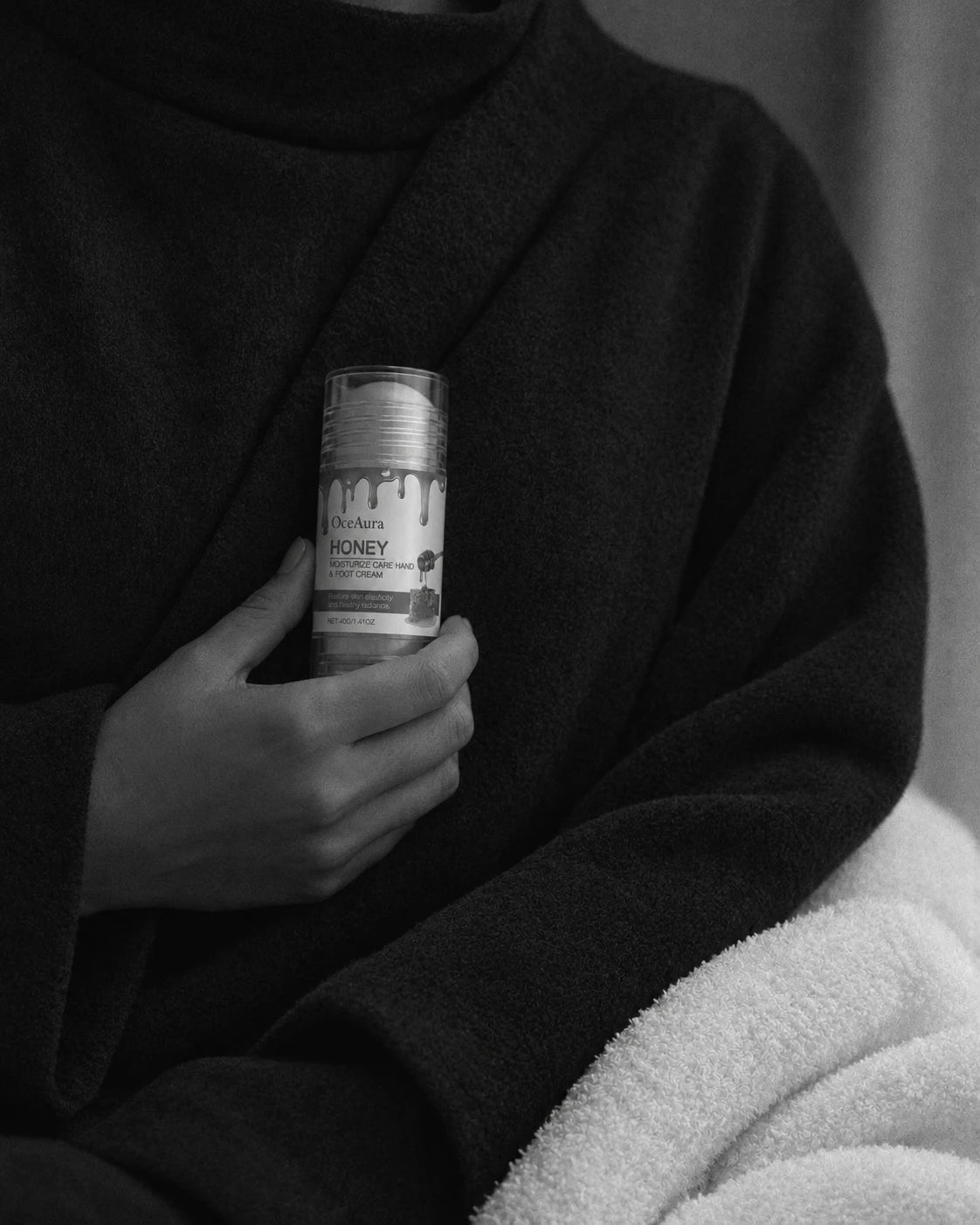 Honey Hand & Foot Cream Stick held against a dark robe